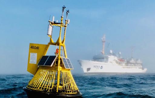 An yellow ocean acidification buoy located in the Pacific Ocean off the central Washington coast with the NOAA Ship Fairweather in the background. 