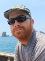 Patrick Berk with sunglasses and hat in front of water