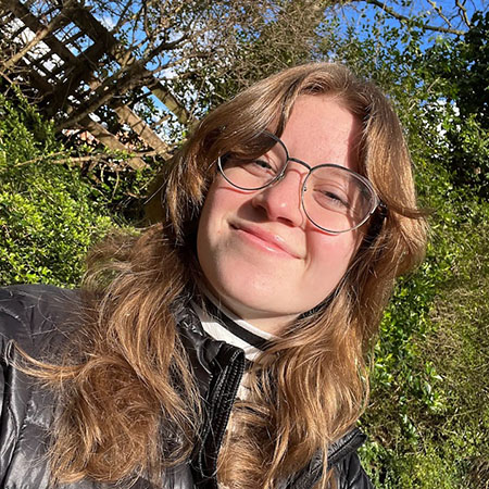 Esther in front of trees and wooden fence